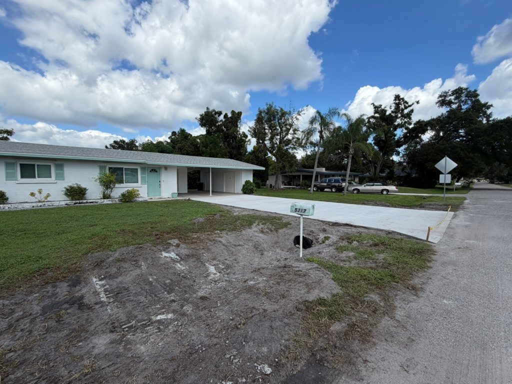 New concrete driveway extending from a residential carport to the street