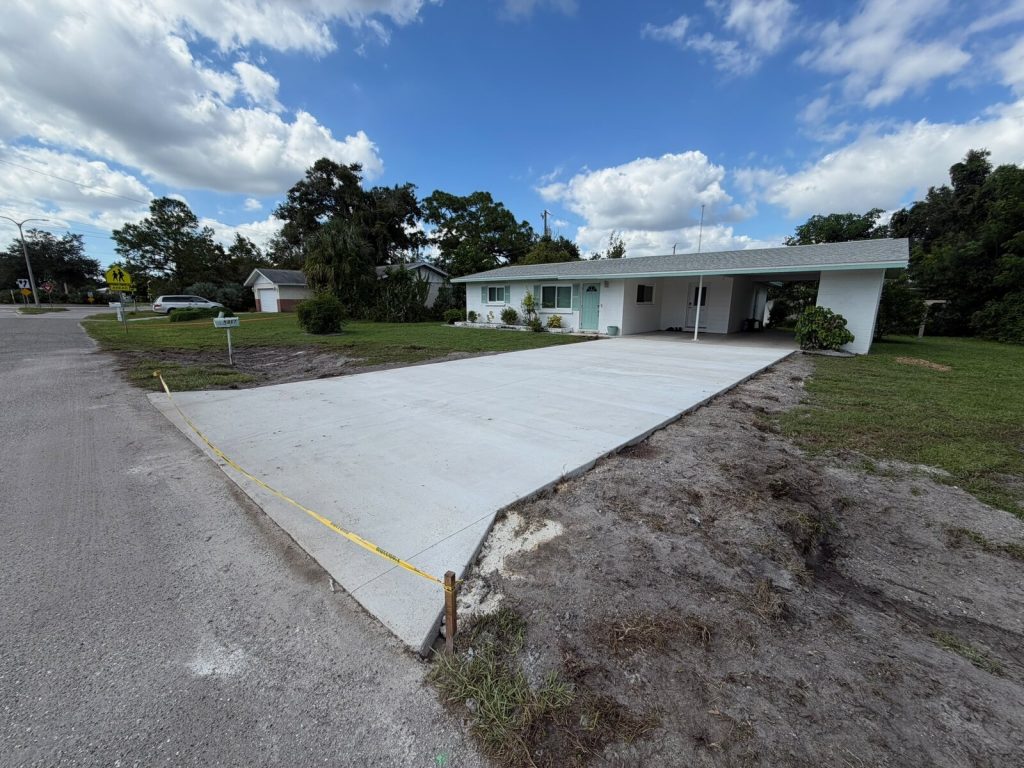 Wide concrete driveway with finished edges and control joints in front of a home