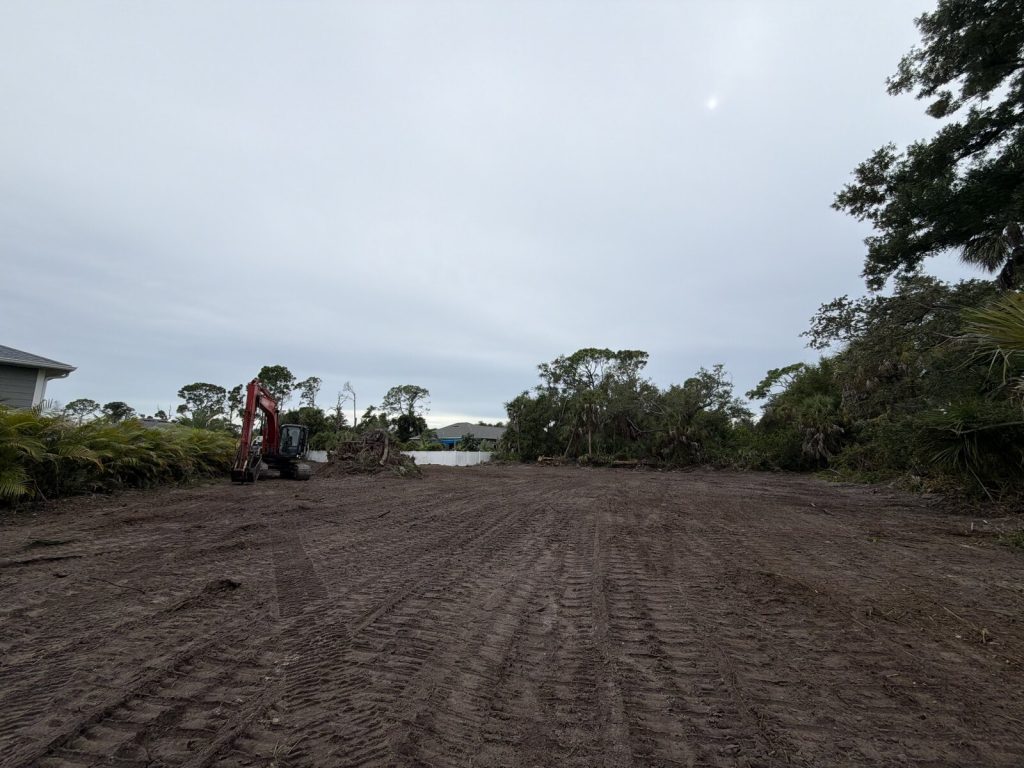 Excavator on a cleared residential lot with freshly graded soil