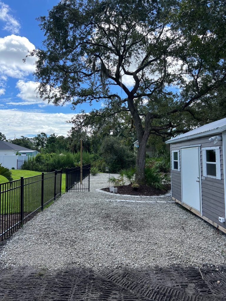 Decorative rock parking area beside a storage shed with paver border