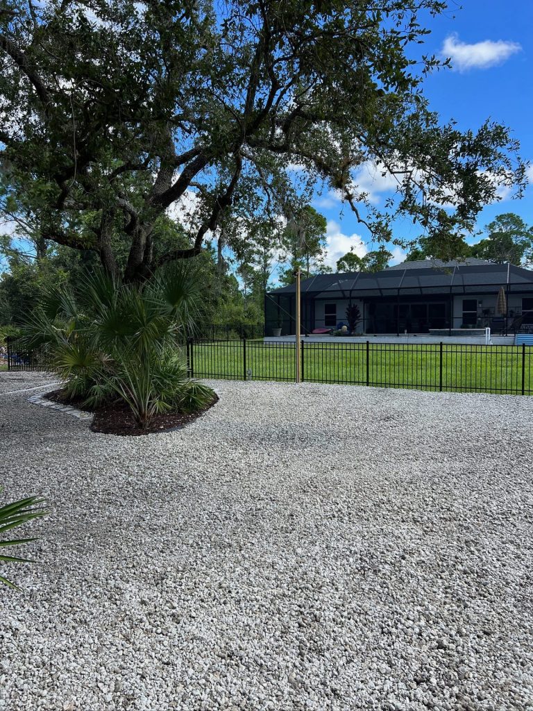 Decorative rock area with mulched palm bed along an aluminum fence