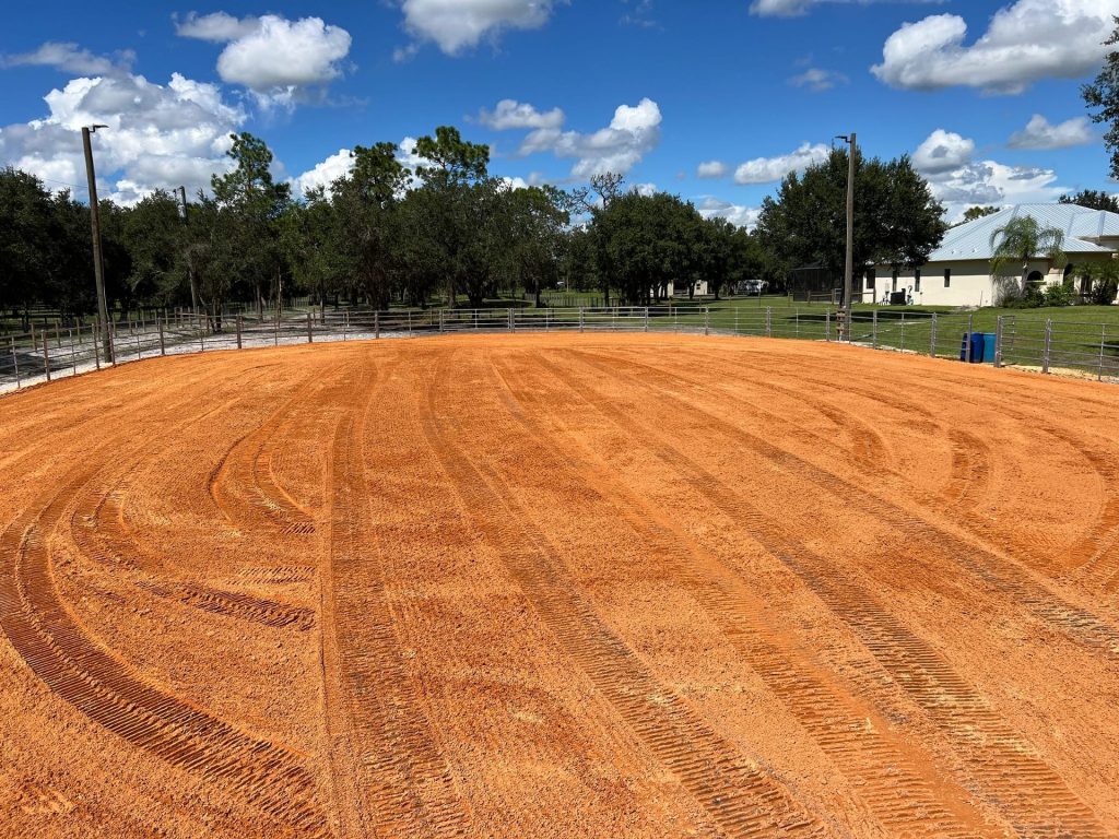 Freshly dragged red clay footing inside a new horse arena in Sarasota County