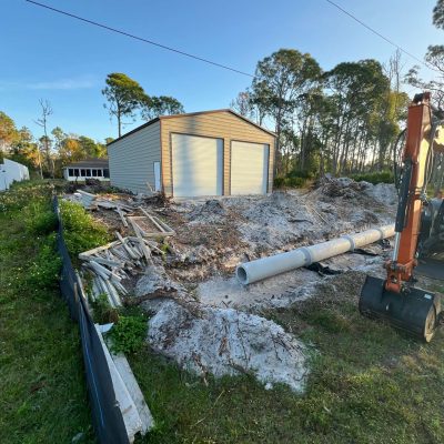 Orange excavator digging a trench for a french drain.