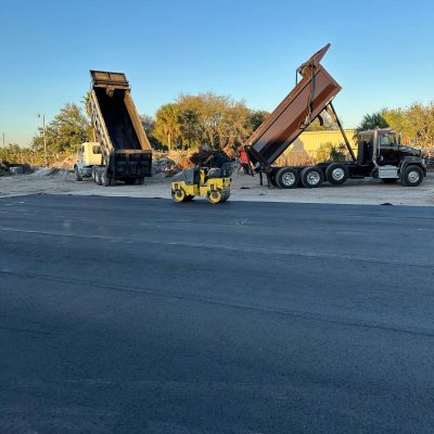 Asphalt paving equipment; dump trucks and road roller.