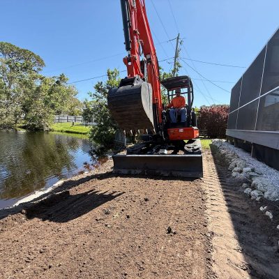 Excavator smoothing out soil and prepping for hardscaping.