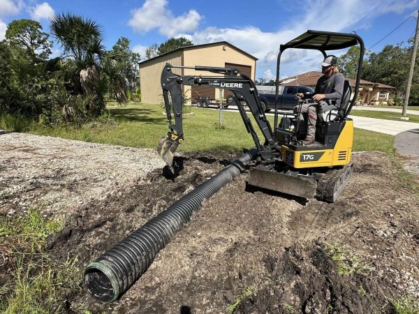 Yellow excavator digging out a culvert to be installed.