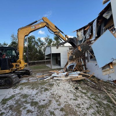 Yellow excavator used to demolition a yellow barn.