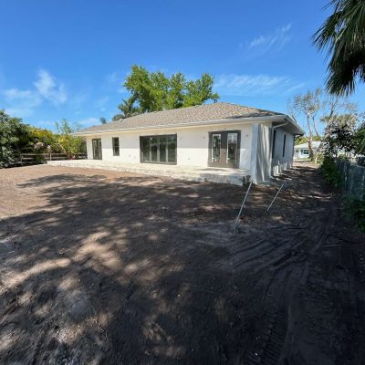 Yard graded with excavation equipment to prepare for sod installation.