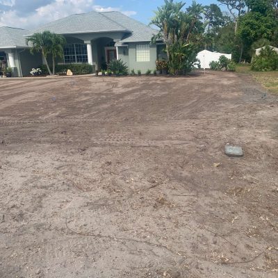 Yard graded with excavation equipment to prepare for sod installation.